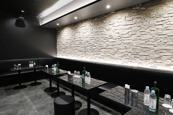 Modern black lounge with stone accent wall, low glass tables, and bottle water on the tables for guests.